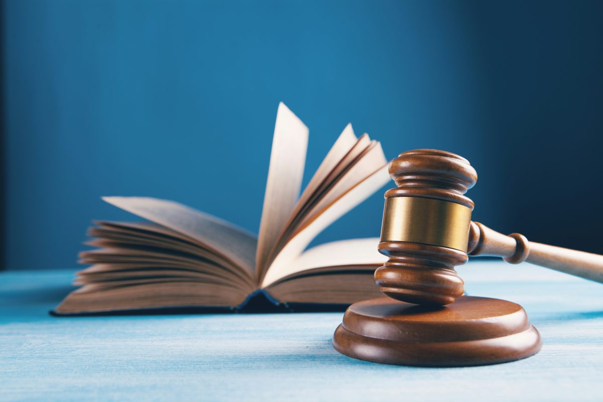wooden gavel on table with open book behind it