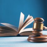 wooden gavel on table with open book behind it
